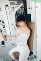 A woman in a white top and white pants working out in a gym.