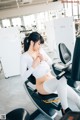 A woman sitting on a stationary bike in a gym.