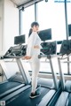 A woman standing on a treadmill in a gym.