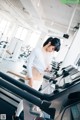 A woman is running on a treadmill in a gym.