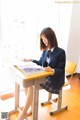 A woman sitting at a desk reading a book.