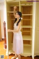 A woman in a white dress standing in front of a wardrobe.