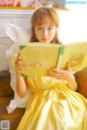 A little girl in a yellow dress reading a book.