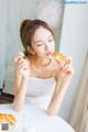 A woman sitting at a table eating a croissant.