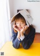 A woman sitting at a table with a book on her head.