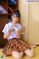 A young woman sitting on the floor reading a book.