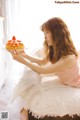 A woman sitting on a bed holding a plate of food.