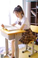 A young woman sitting at a desk reading a book.