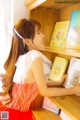 A woman in a red dress is looking at a book shelf.