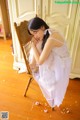 A woman in a white dress sitting on a wooden chair.