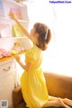 A little girl in a yellow dress sitting on a couch.