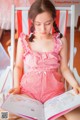 A young girl sitting in a chair reading a book.