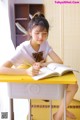 A young woman sitting at a desk writing in a book.