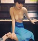 A naked woman sitting on top of a piano.