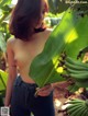 A naked woman standing in front of a bunch of bananas.