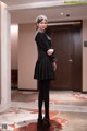 A woman in a black dress standing in a hallway.