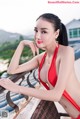 A woman in a red bikini posing on a balcony.