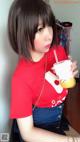 A woman in a red shirt holding a cup of coffee.