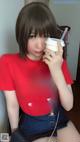 A woman in a red shirt holding a cup of coffee.