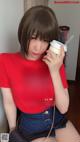 A woman in a red shirt holding a cup of coffee.