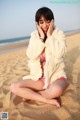 A woman sitting on the sand on a beach.