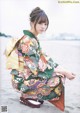 A woman in a colorful kimono sitting on the beach.