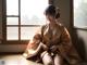 A woman in a kimono sitting on a window sill.