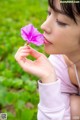 A woman holding a pink flower in her hand.