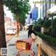 A woman pushing a shopping cart down a sidewalk.