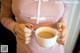 A woman holding a cup of tea with a spoon in it.