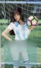 A woman holding a soccer ball in front of a goal.