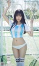 A woman in a blue and white soccer uniform posing in front of a goal.