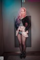 A woman with pink hair standing in front of a door.