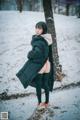 A woman in a black coat is standing in the snow.