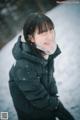 A woman wearing a black jacket standing in the snow.