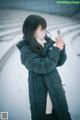 A woman wearing a face mask taking a picture of herself in the snow.