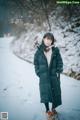 A woman standing in the snow wearing a black coat.