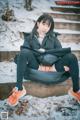 A woman sitting on a bench in the snow.