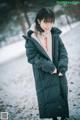 A woman wearing a black coat standing in the snow.