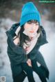 A woman wearing a blue hat and scarf in the snow.