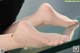 A woman wearing a gold ankle bracelet on a glass table.