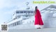 A woman in a red cape standing in front of a large boat.