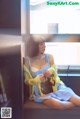 A woman sitting on a window sill reading a book.