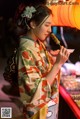 A woman in a kimono eating a piece of food.