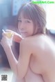 A naked woman holding a cup of coffee in her hand.