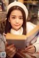 A woman in a white hat is reading a book.