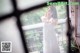 A woman in a white dress standing on a balcony.