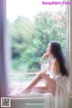 A woman sitting on a window sill looking out the window.