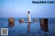 A woman in a white dress standing in the water.