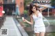 A woman in a white tank top and shorts holding an ice cream cone.